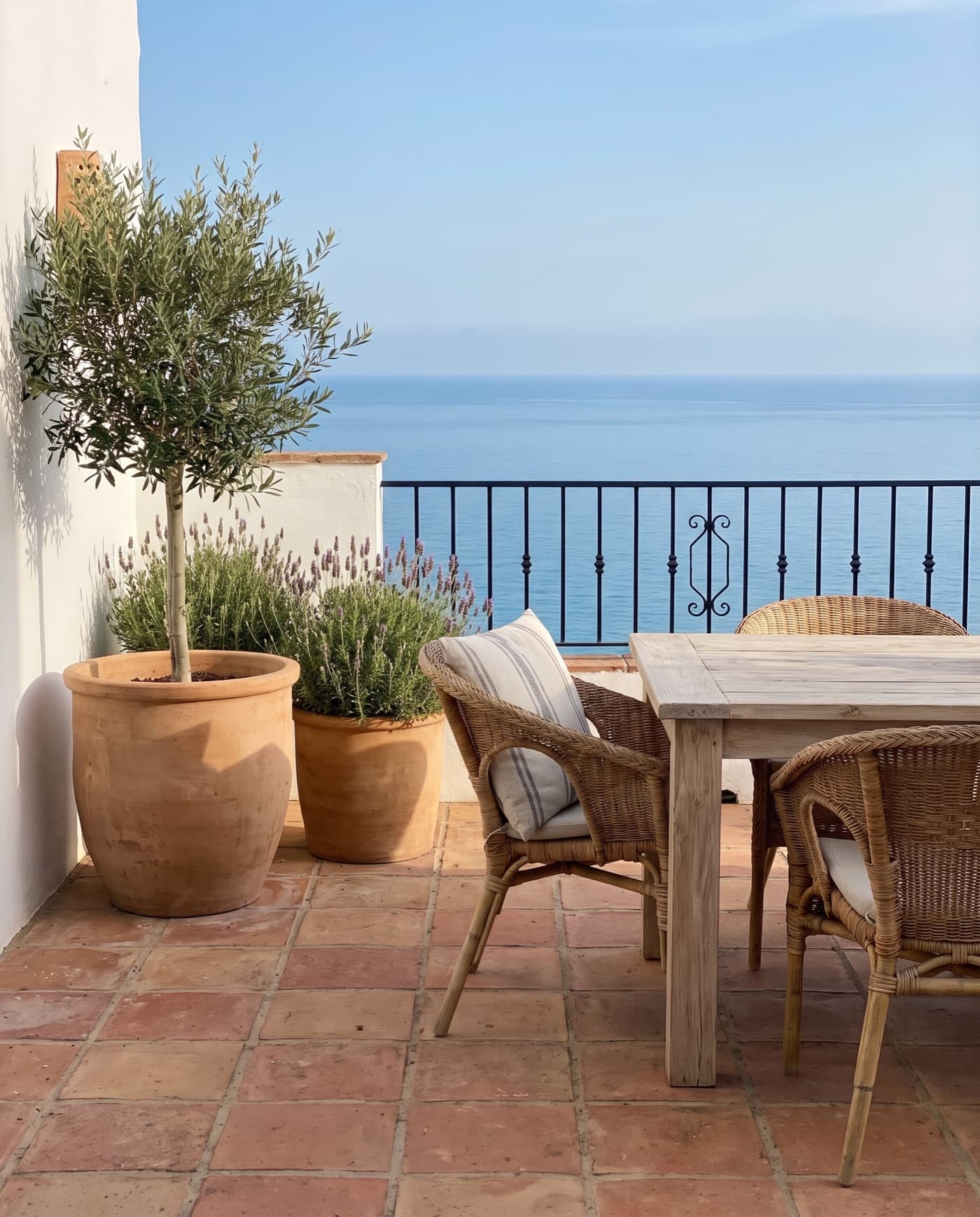 Terraza soleada con olivo, mesa de madera y vistas al mar